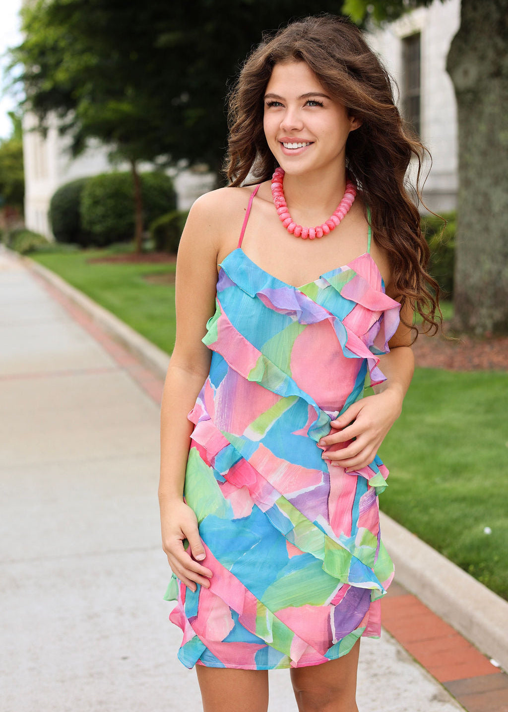 Woman wearing a colorful dress with ruffled layers outdoors.