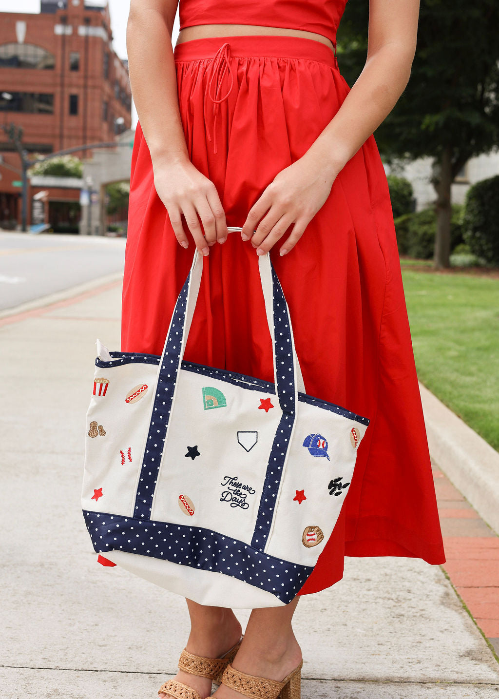 Person holding a tote bag with various designs outdoors