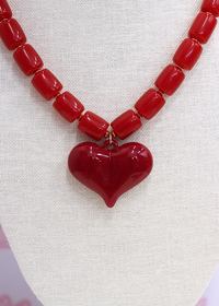 Red heart-shaped pendant necklace on a textured white background