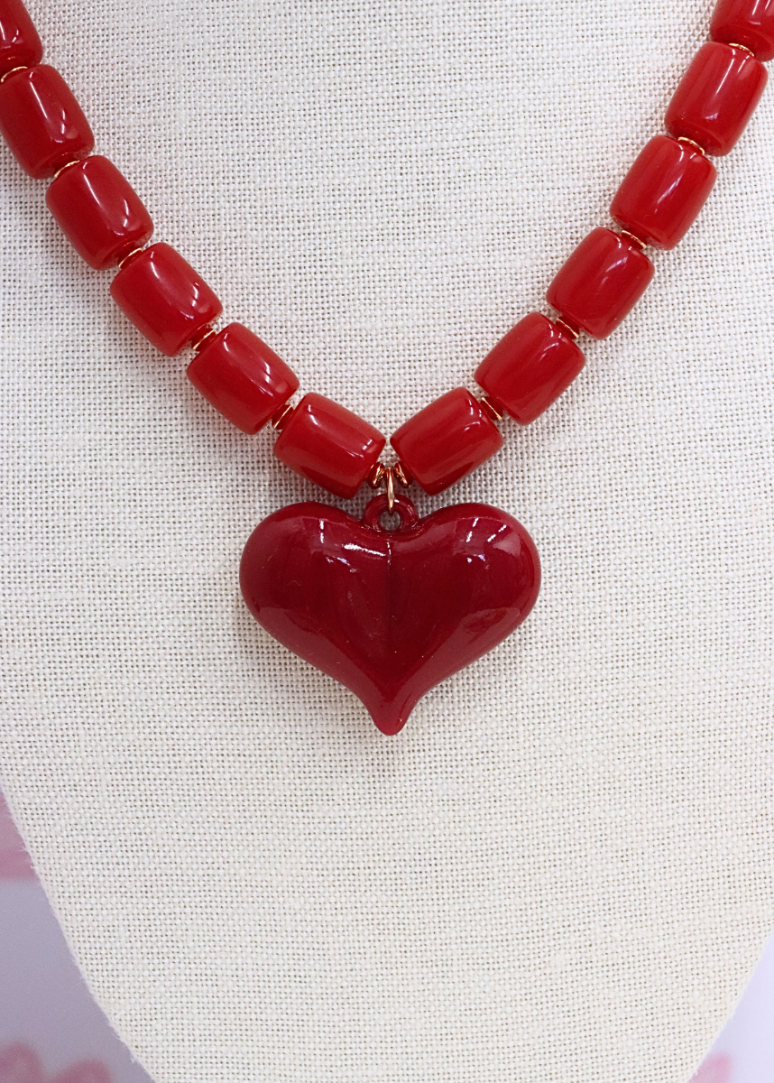 Red heart-shaped pendant necklace on a textured white background