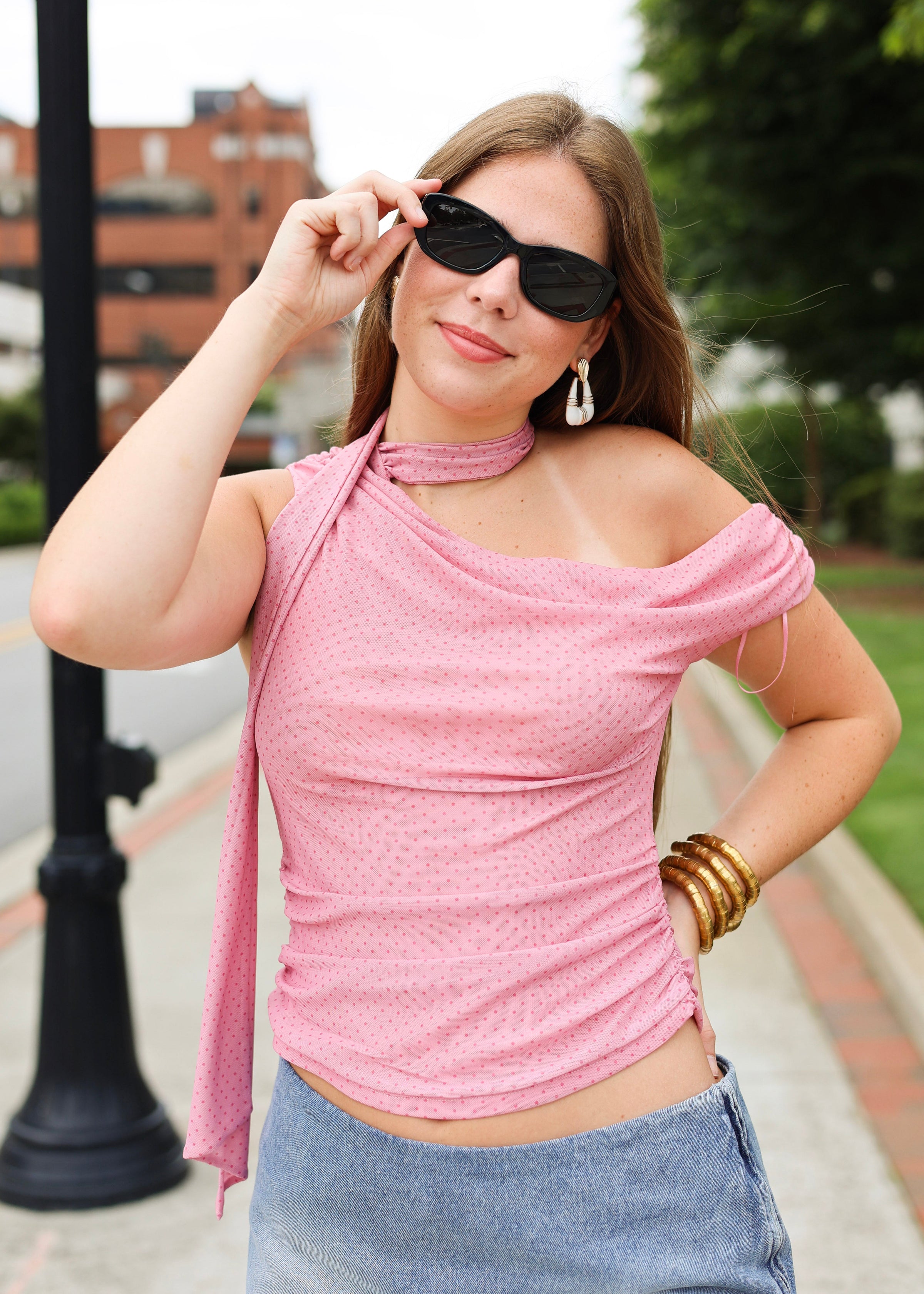 Woman wearing a pink top and denim skirt outdoors