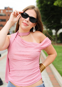 Woman wearing a pink top and sunglasses outdoors