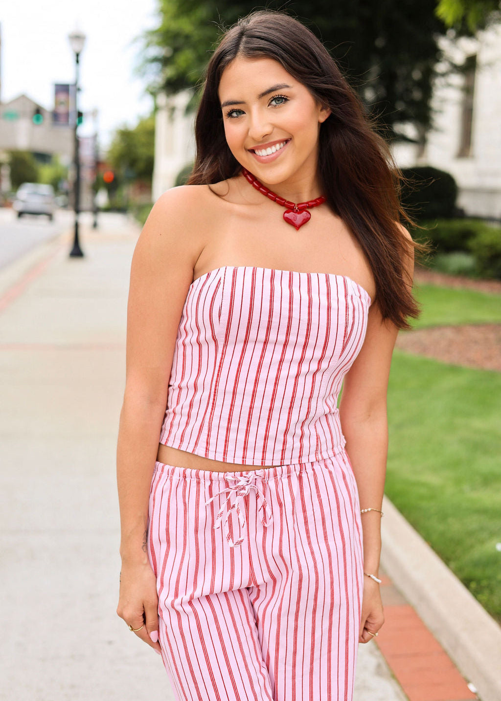 Woman wearing a red and white striped outfit on a sidewalk.