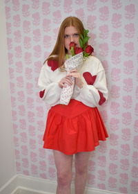 Close-up of red heart design on cream knit sweater