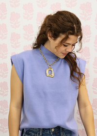 Baby blue sleeveless mock neck knit top styled with denim outfit and gold statement necklace