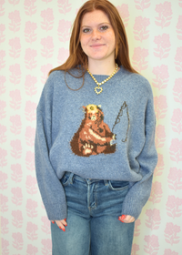 Sweater with bear fishing on it styled with jeans and gold necklace