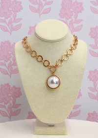 Close up of gold dome pendant necklace with pearl detail