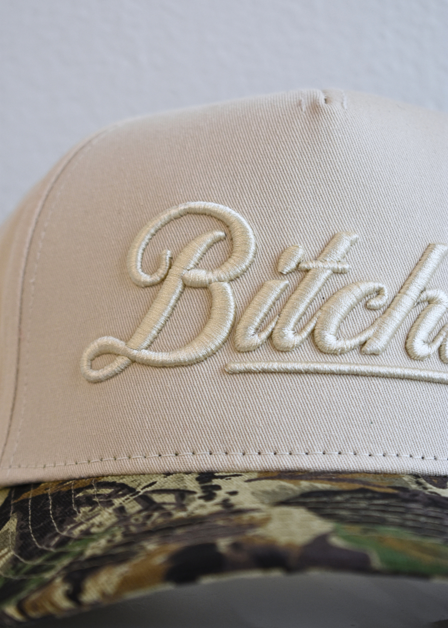 Close up of Bitchin embroidery on camo trendy trucker hat