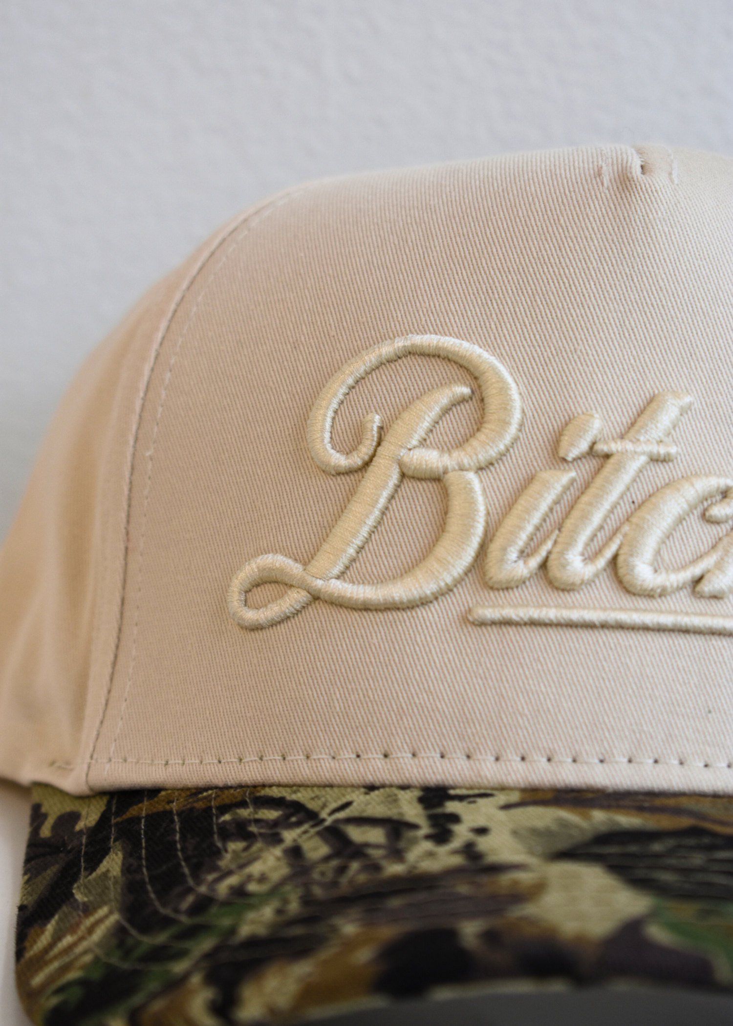 Close up of Bitchin embroidery on natural trendy trucker hat