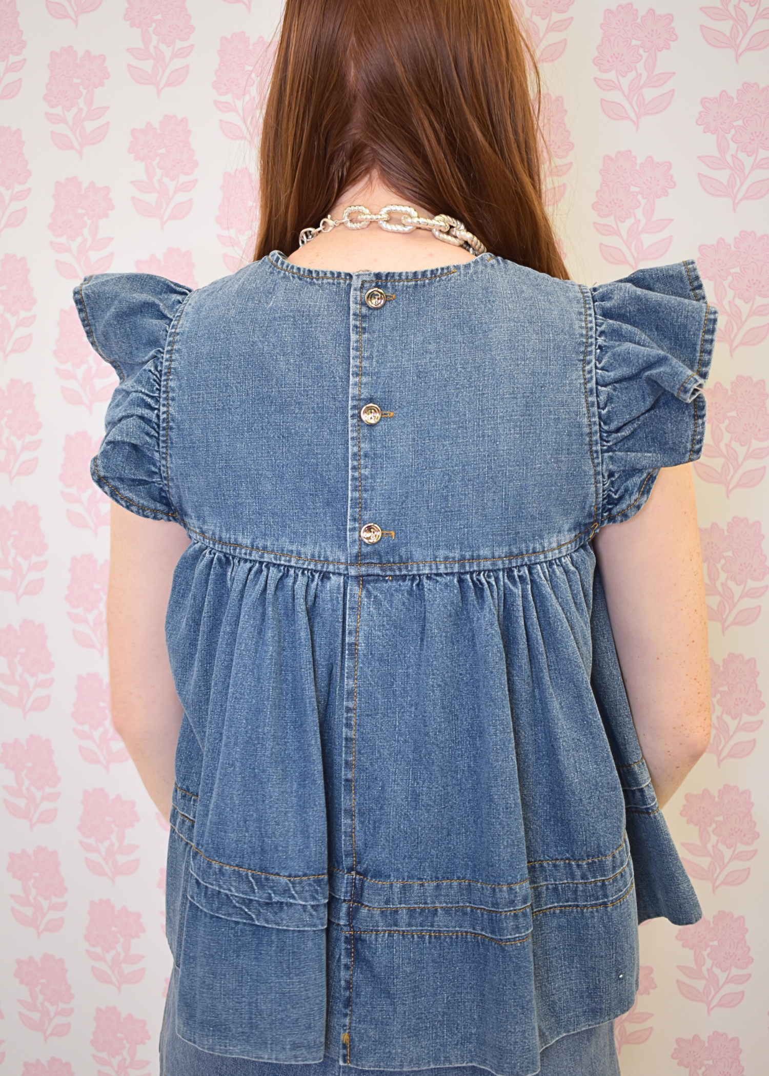 Back view of women’s denim babydoll blouse with relaxed fit and gathered detail