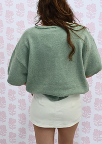 Close up of knit fabric on light green short sleeve cardigan