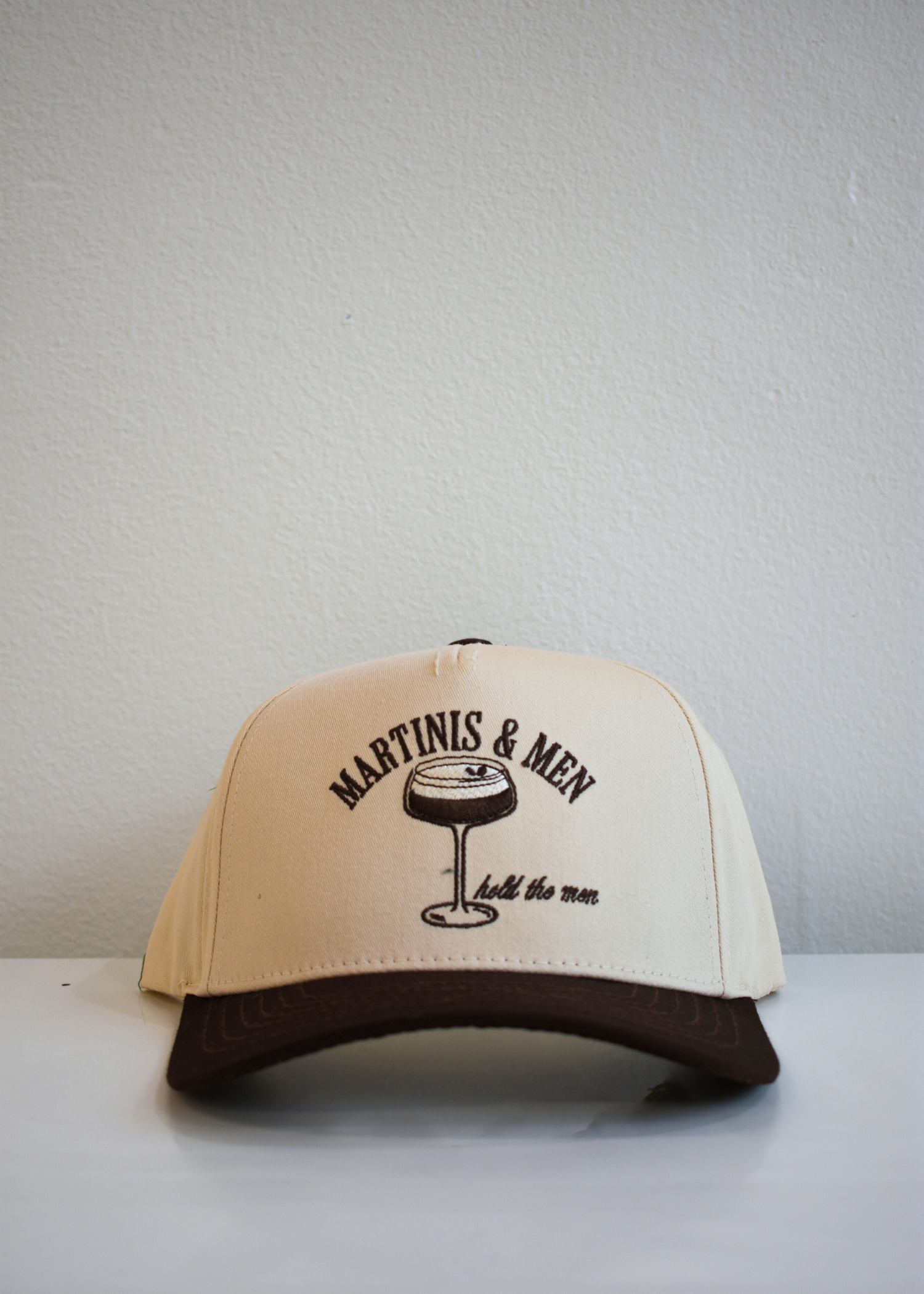 Front view of Martinis and Men brown and natural vintage trucker hat with embroidered martini glass design