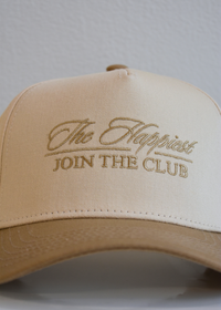 Tan embroidered cursive trucker hat on natural background