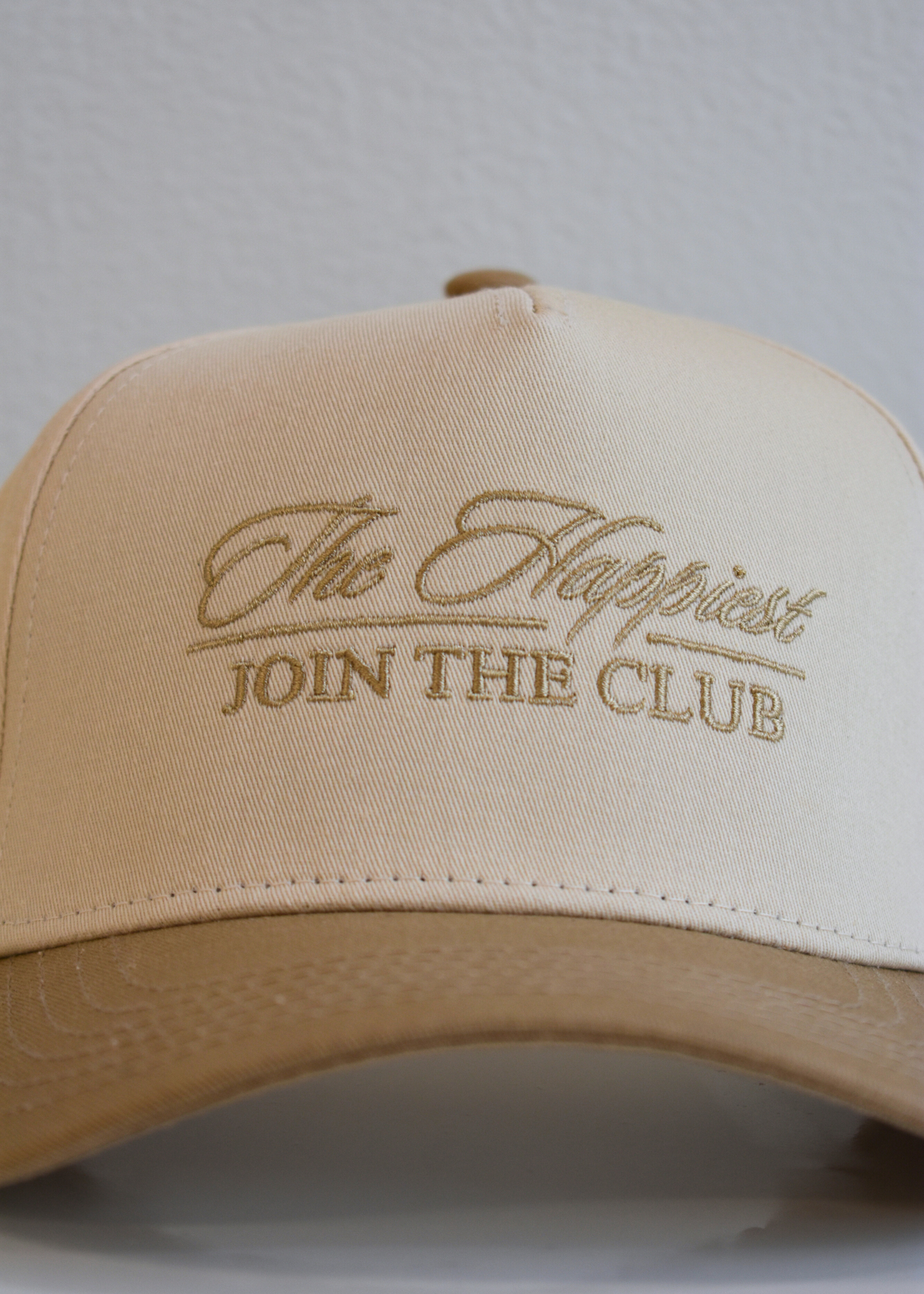 Tan embroidered cursive trucker hat on natural background