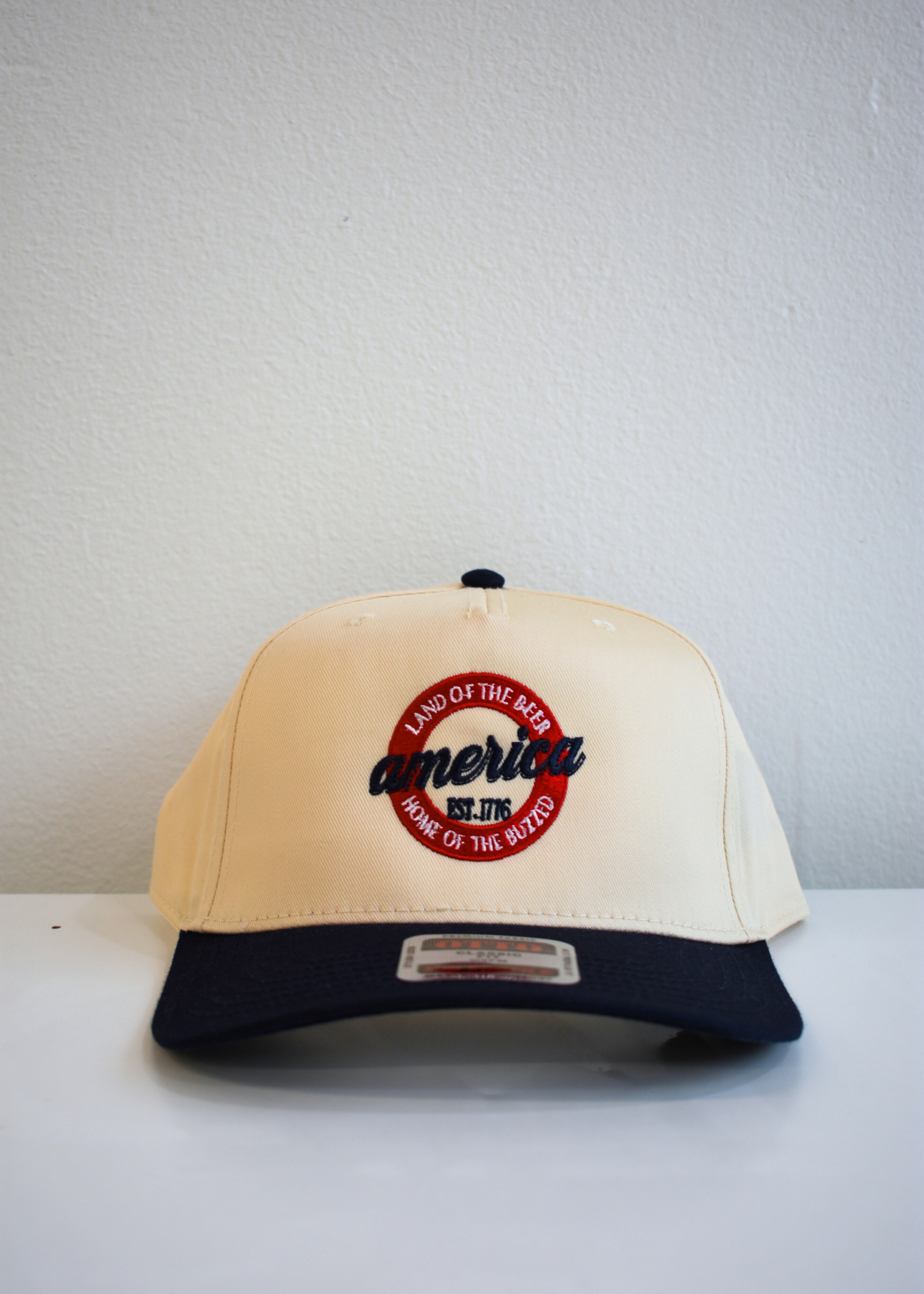 Close up of America Land of the Beer Home of the Buzzed embroidery on navy snapback hat