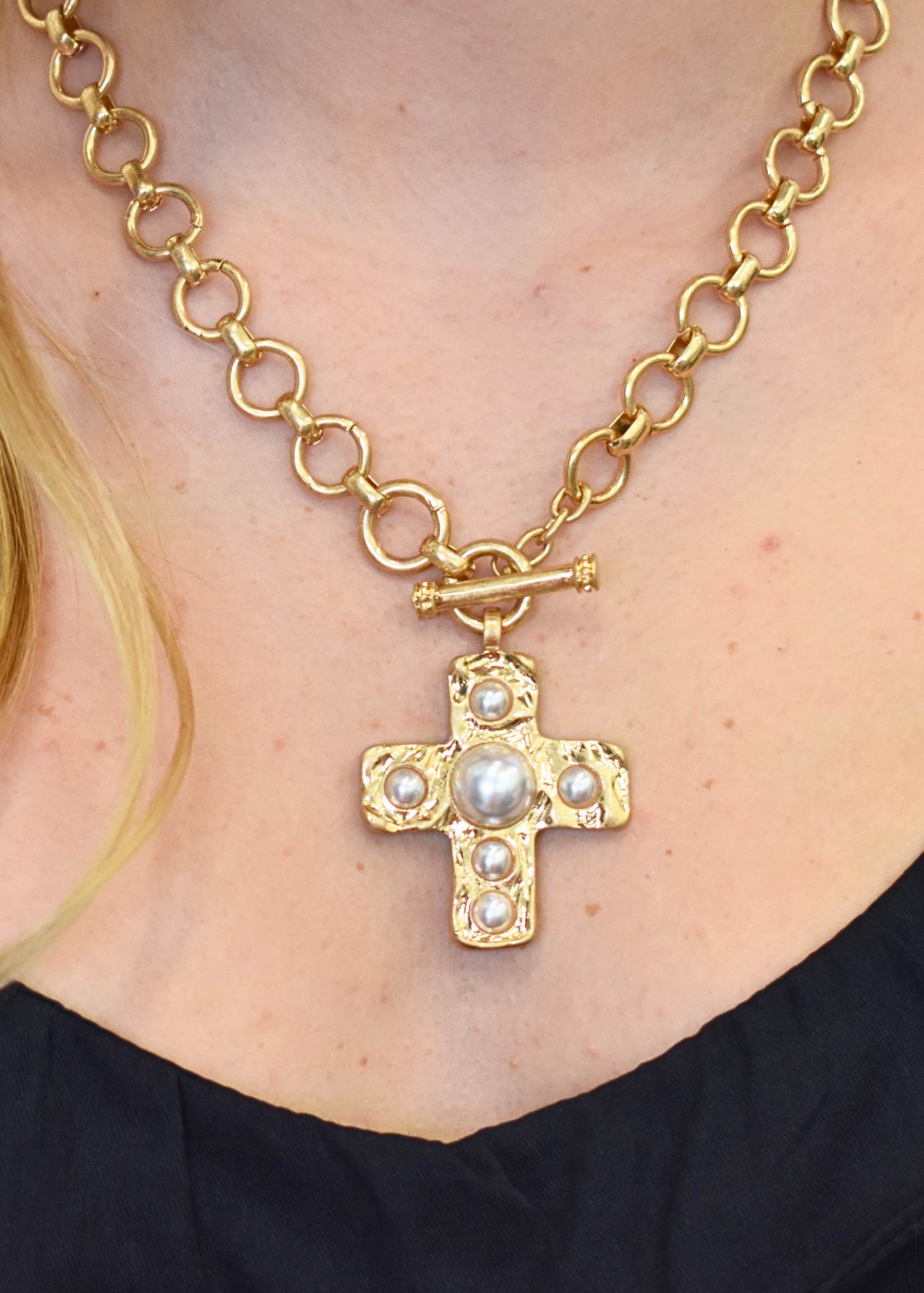Pavé pearl cross necklace with matching stud earrings in gold styled with navy skirt and tank top set