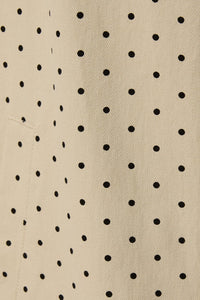 Close up of polka dot pattern on beige denim trench coat