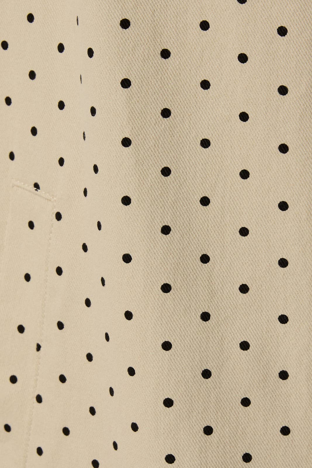 Close up of polka dot pattern on beige denim trench coat