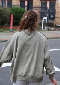 Close up of vintage wash graphic detail on olive sweatshirt