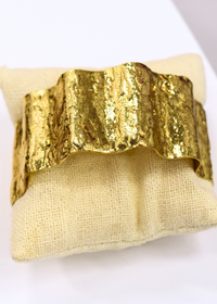 Sleek gold cuff bracelet featuring wave inspired shape