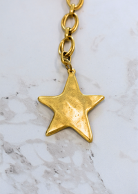 Star shaped gold bag charm with playful wavy design