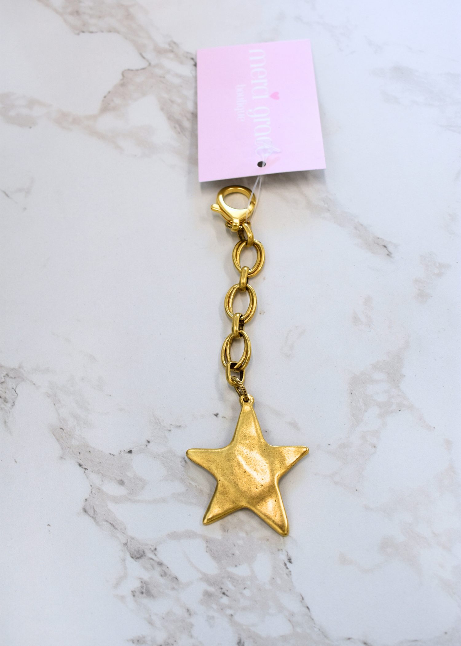 Gold wavy star bag charm with chain detail